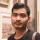 IDP IELTS test taker Adi in front of artwork - A person with a blurred face standing in front of a wall displaying framed artwork, including paintings or photographs
