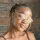 IDP IELTS test taker Elsie in front of brick wall - A person with a blurred face, braided hair, wearing earrings and a sleeveless top, standing in front of a brick wall